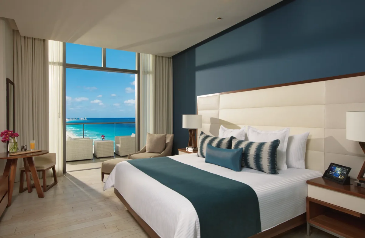 Deluxe Ocean View room with king bed and furnished balcony overlooking the turquoise Caribbean at Secrets The Vine Cancun.