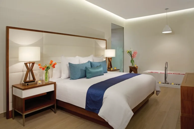 Preferred Club Presidential Suite bedroom with king bed, soaking tub, and modern open bathroom at Secrets The Vine Cancun.