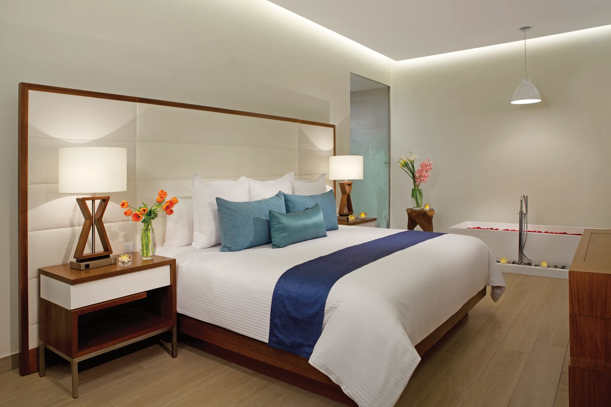 Preferred Club Presidential Suite bedroom with king bed, soaking tub, and modern open bathroom at Secrets The Vine Cancun.