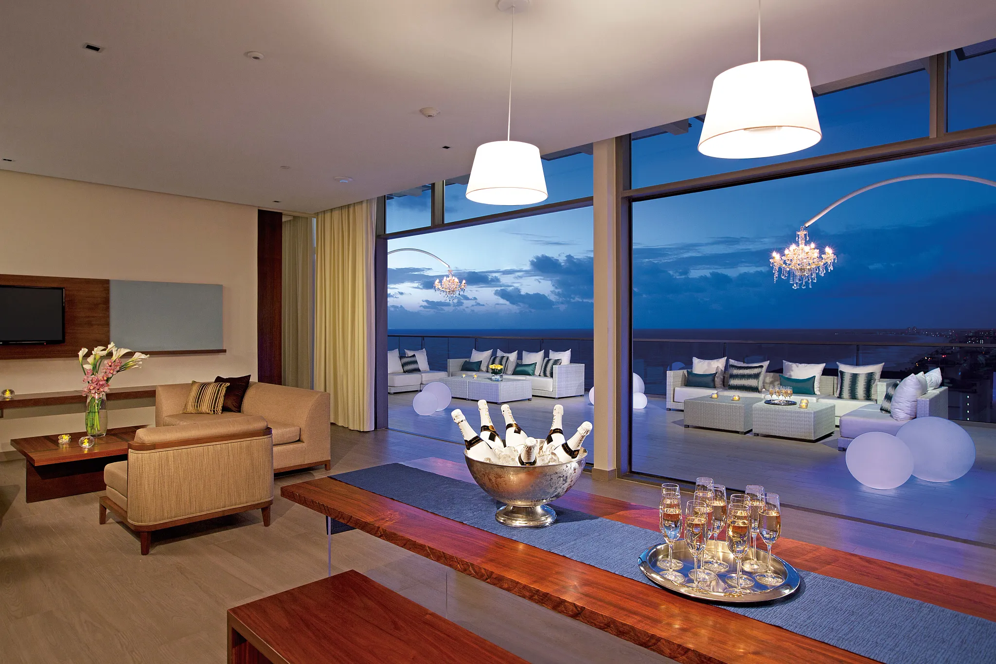Preferred Club Presidential Suite living area with champagne setup and oceanfront terrace at night in Cancun.