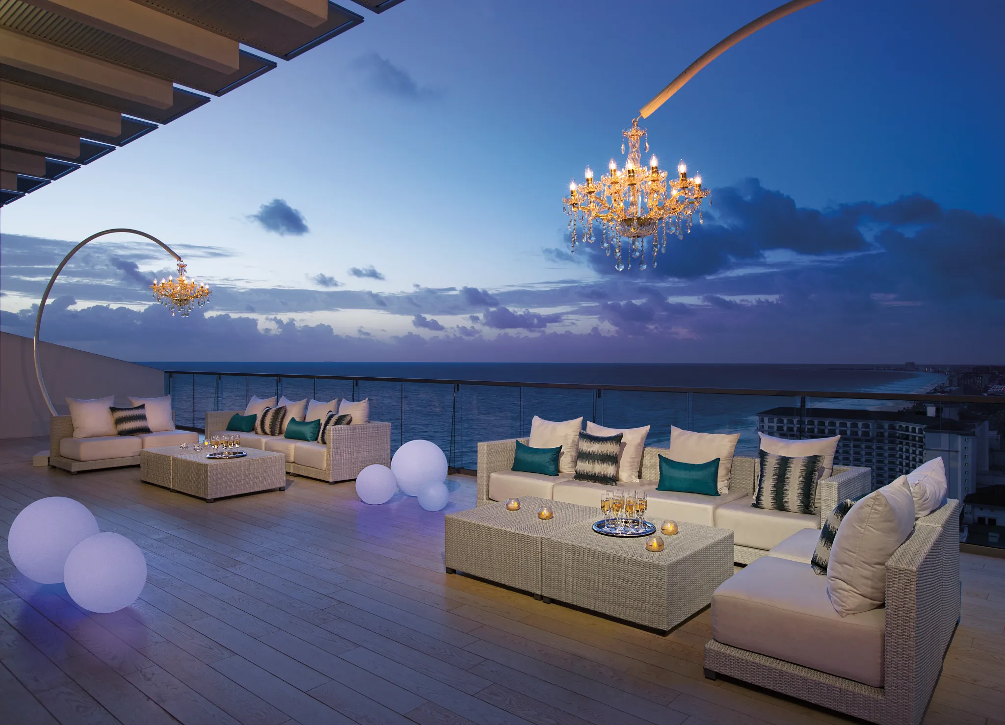 Preferred Club Presidential Suite terrace at night with chandeliers, lounge seating, and ocean views in Cancun.